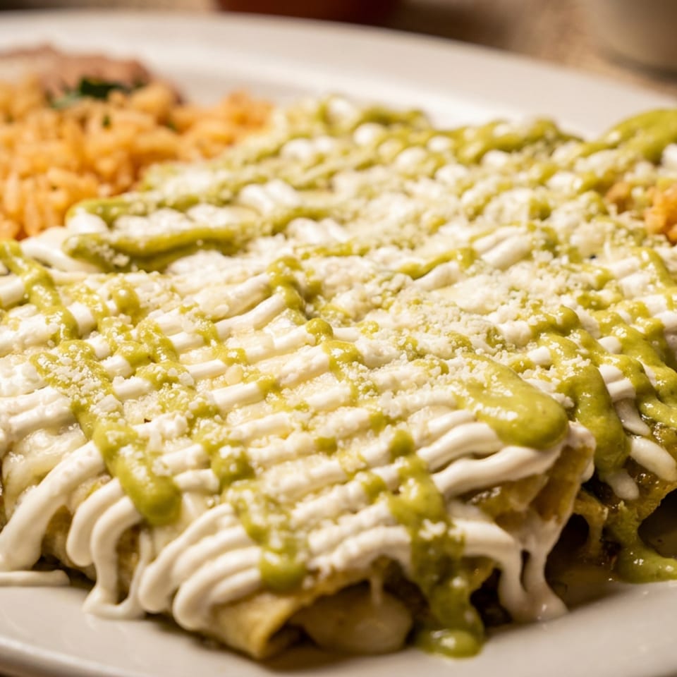Enchiladas with green sauce, sour cream, and cheese, served with rice and refried beans.